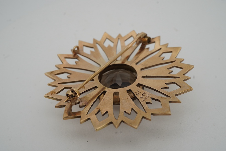 A smoky quartz brooch, set with a circular-cut smoky quartz, within a floral gold surround, 5.7cm diameter, stamped 9CT, maker's mark JF, stamped IVSS, gross weight 17 grams